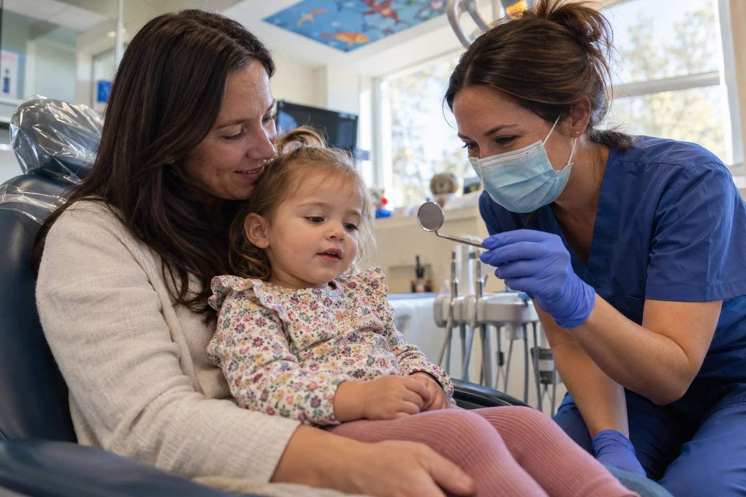A toddler on a parent's lap at a first dental visit