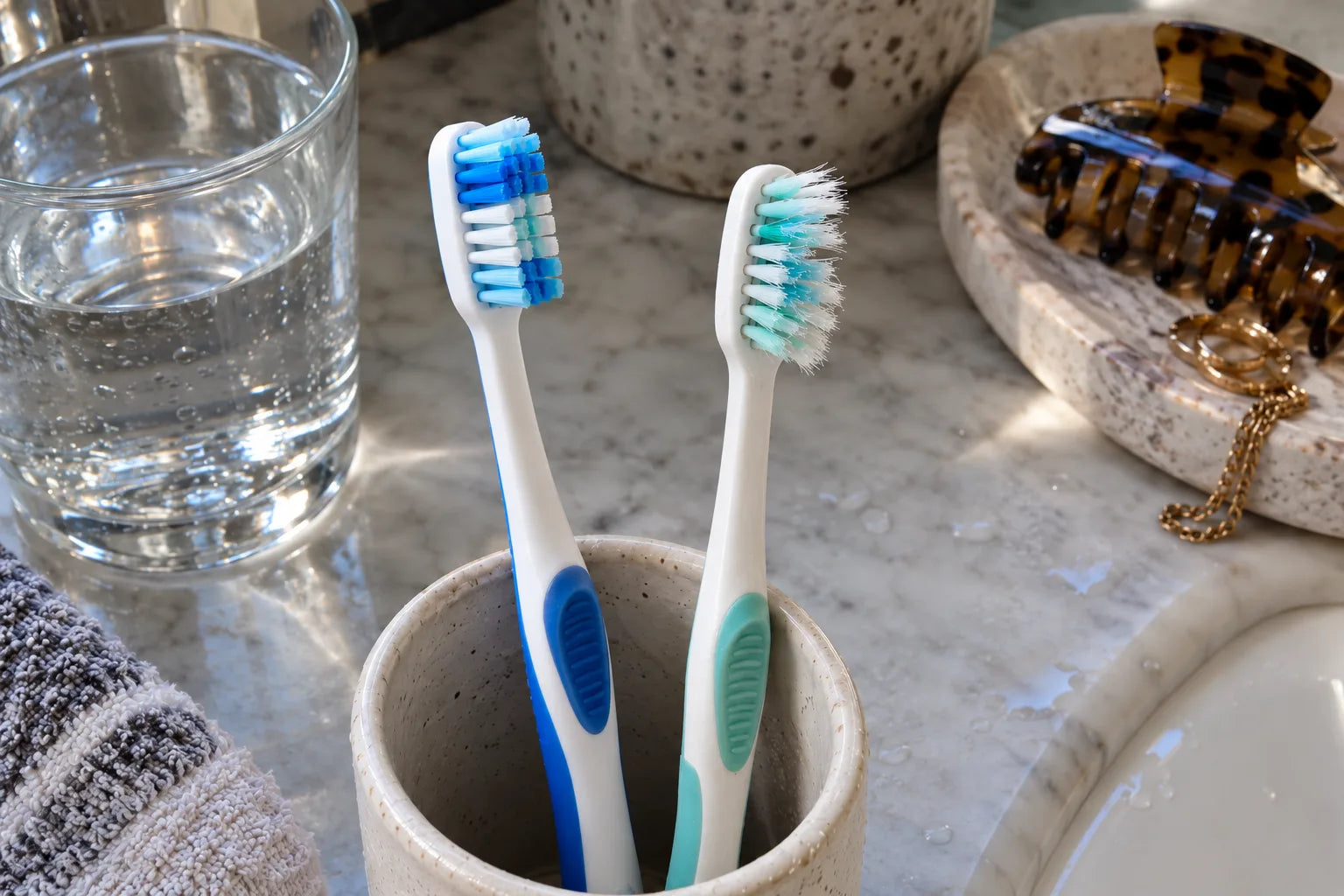 A new toothbrush next to a worn one with splayed bristles