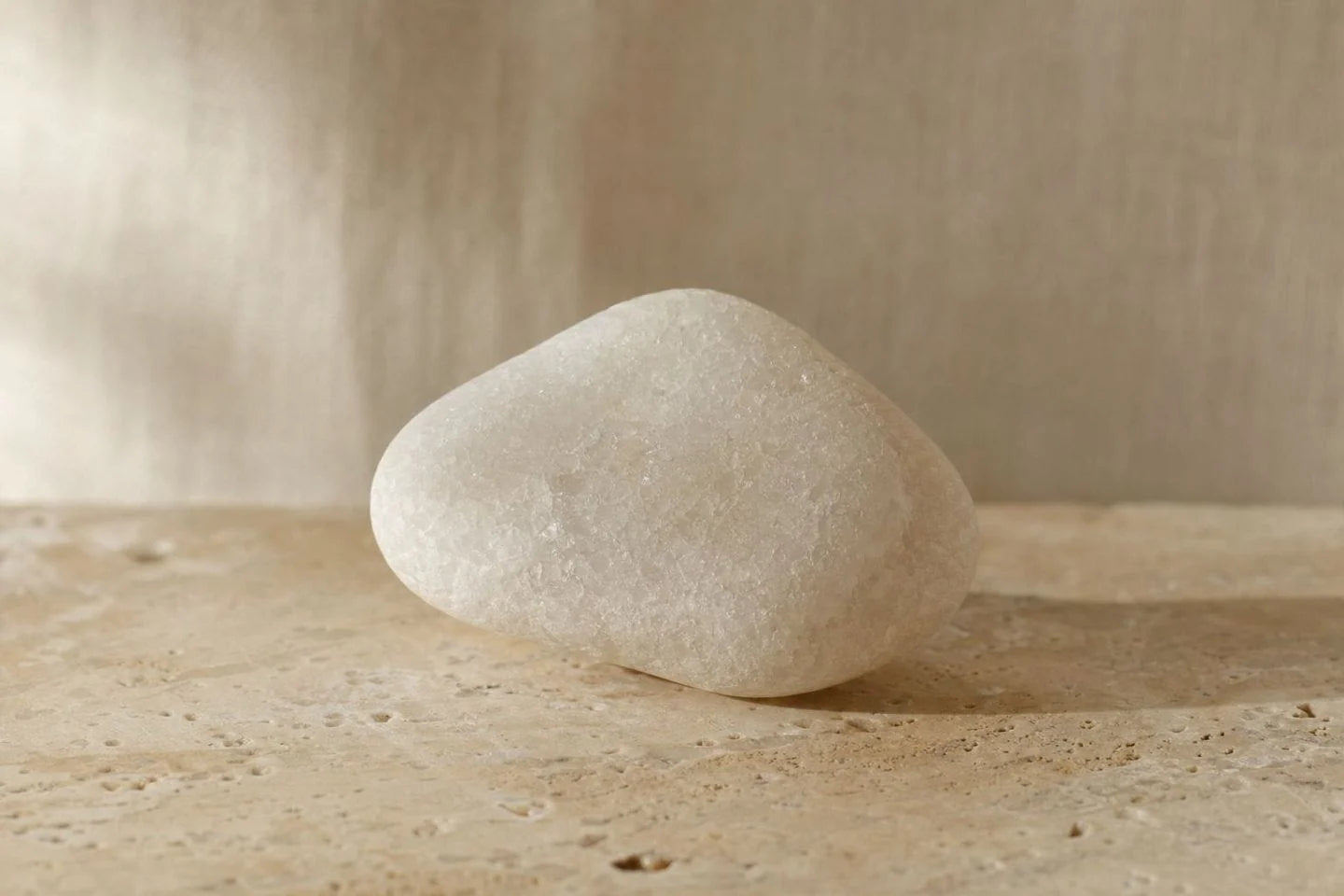 A smooth white mineral stone on a travertine surface